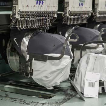 Row of hats being embroidered by industrial embroidery machines